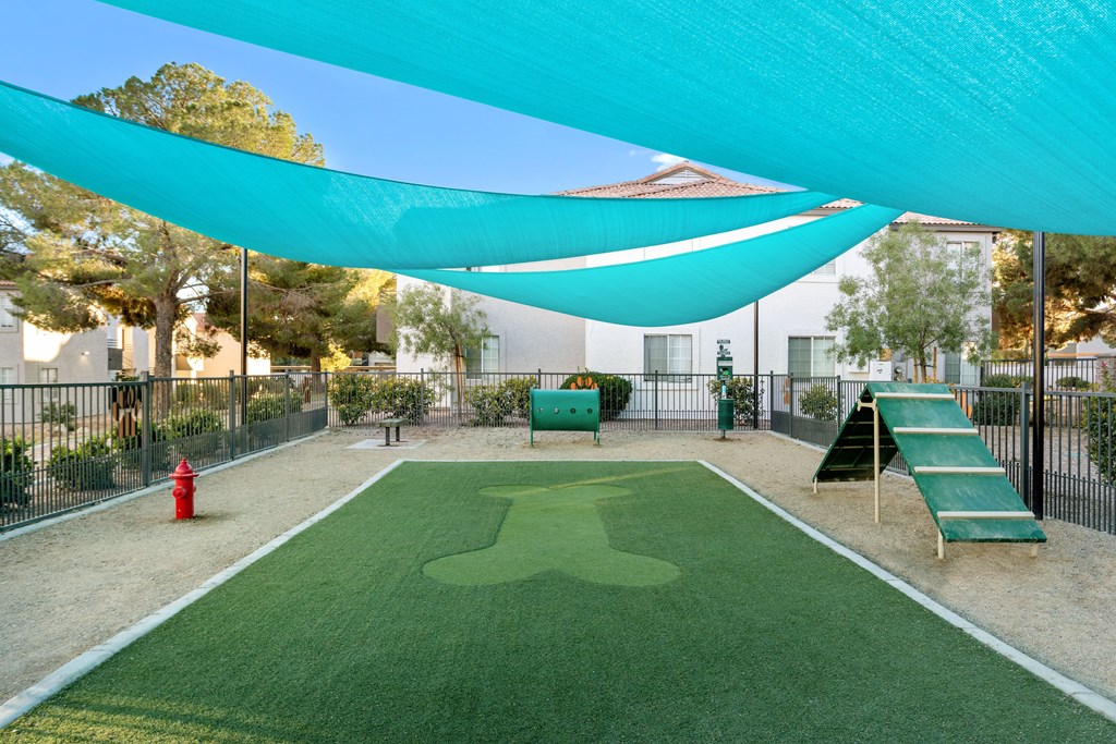 a green astroturf baseball field with a blue awning overhead
